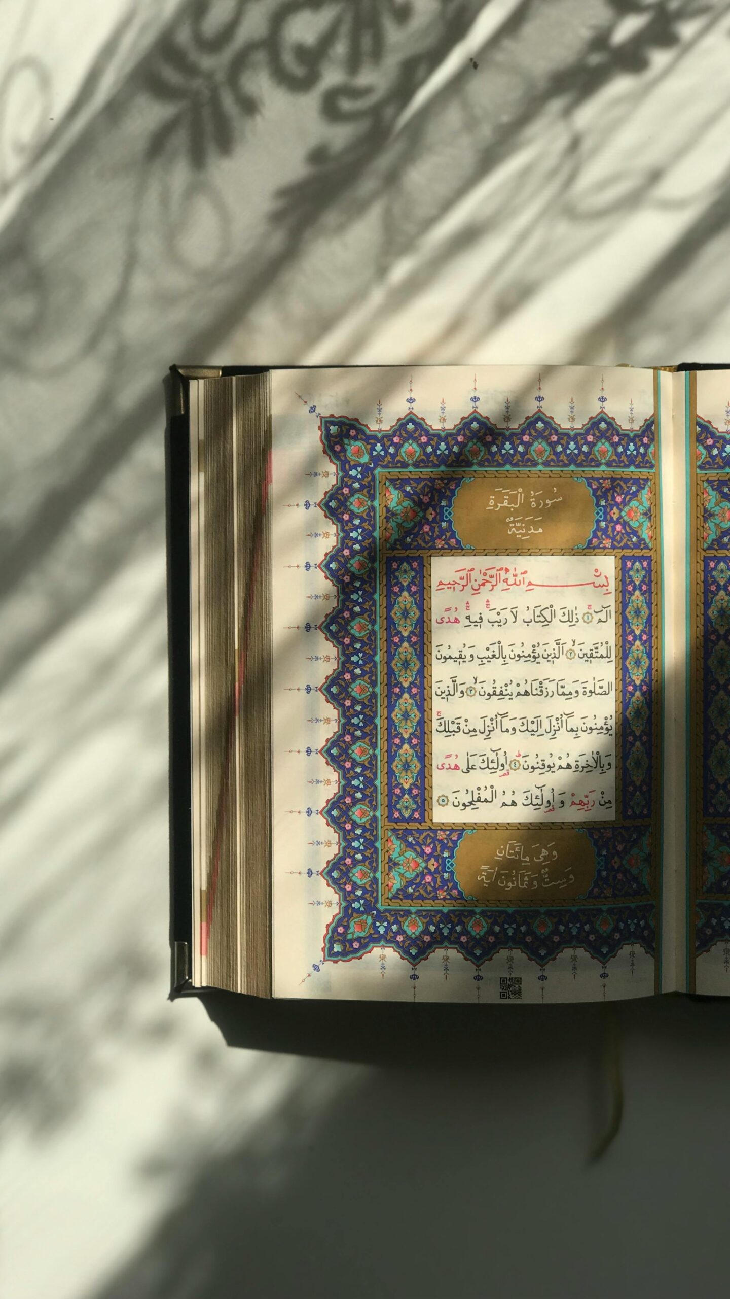 An open quran book on a table with shadows